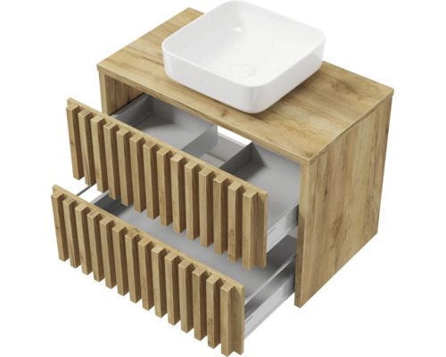 Meuble sous-vasque aspect chêne avec deux tiroirs ouverts à façades à lattes et une vasque à poser blanche.
