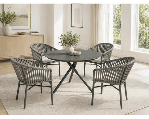 Salle à manger moderne avec une table ronde et quatre fauteuils en corde tressée avec coussins clairs dans une pièce lumineuse.