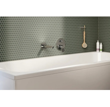 Modernes Badezimmer mit grünen Mosaikfliesen in Wabenoptik an der Wand hinter einer weißen Badewanne mit verchromten Armaturen.