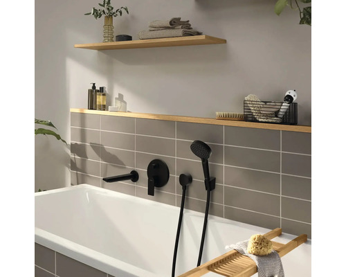 Baignoire moderne avec robinetterie encastrée noir mat, carrelage gris et étagères en bois avec accessoires de salle de bain.