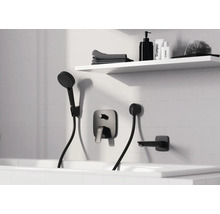 Salle de bains moderne avec mitigeur de baignoire encastré noir, douchette et bec déverseur sur mur carrelé blanc avec étagère.