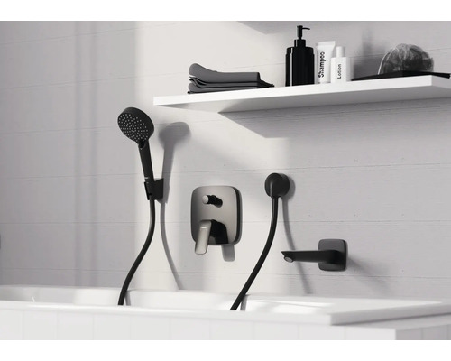 Salle de bains moderne avec mitigeur de baignoire encastré noir, douchette et bec déverseur sur mur carrelé blanc avec étagère.
