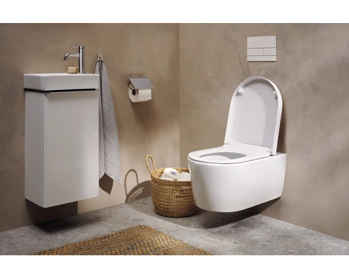 Modernes Gäste-WC mit wandhängender Toilette, weißem Waschtischunterschrank, Handwaschbecken und Aufbewahrungskorb vor Wänden in Betonoptik.