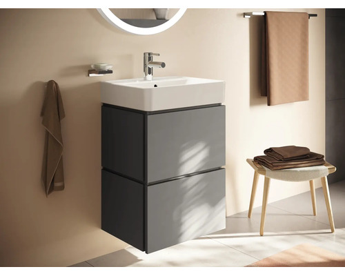 Moderner wandhängender Waschtischunterschrank mit Keramikwaschbecken, zwei Schubladen und beleuchtetem Spiegel in einem hellen Badezimmer.
