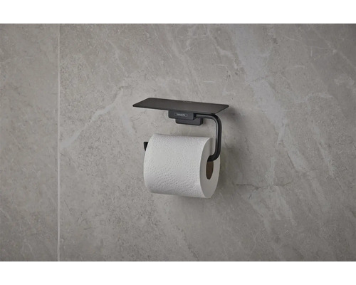 Porte-papier toilette hansgrohe noir mat avec tablette, monté sur un mur à l'aspect pierre naturelle.
