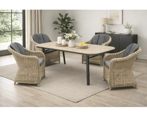 Ensemble de salle à manger avec table rectangulaire aspect bois et quatre fauteuils en rotin avec coussins gris dans une pièce lumineuse.