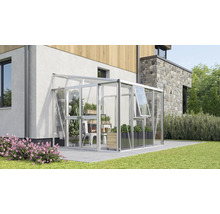 Modernes Anlehngewächshaus aus Aluminium und Glas, an einer Hauswand auf einer Terrasse mit Pflanzen im Inneren.