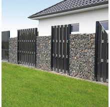 Clôture de jardin moderne composée de gabions avec des pierres grises et des brise-vue verticaux sombres sur une pelouse.