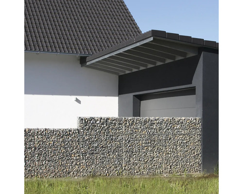 Moderner Gabionenzaun mit Steinfüllung vor einer Hausfassade mit Garage, hell und strukturiert gestaltet.