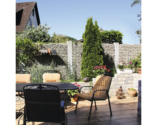 Sitzgruppe auf einer Terrasse mit Gabionenwand, Gartenstühlen mit Auflagen und Gartentisch auf Boden in Holzoptik.