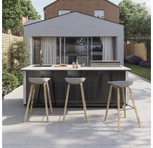 Moderne Außenküche auf gepflasterter Terrasse mit Grill, Spülbecken und Barhockern mit Holzbeinen vor einem Gartenhaus.