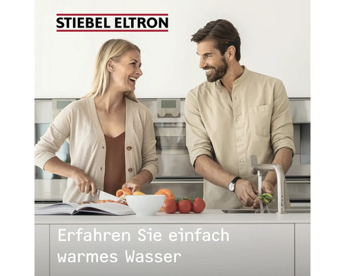 Stiebel Eltron Logo. Couple dans une cuisine moderne et lumineuse lavant et coupant des légumes. Texte: Découvrez simplement l'eau chaude.
