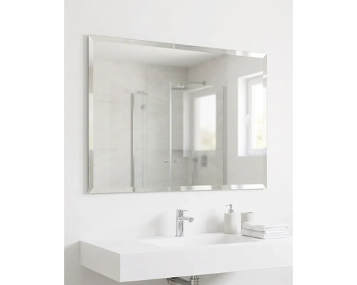 Miroir mural rectangulaire avec bords biseautés au-dessus d'un lavabo blanc moderne dans une salle de bains lumineuse.