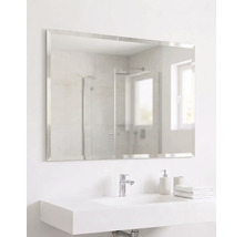Grand miroir de salle de bains rectangulaire avec bord biseauté au-dessus d'un lavabo moderne avec robinet et accessoires.