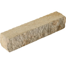 Bloc rectangulaire en pierre naturelle avec une surface rugueuse et texturée.