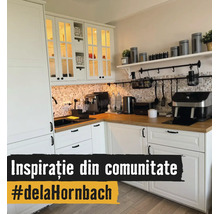 Cuisine en L lumineuse avec armoires blanches, plan de travail en bois, crédence en mosaïque et appareils de cuisine comme une machine à café.