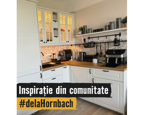 Cuisine en L lumineuse avec armoires blanches, plan de travail en bois, crédence en mosaïque et appareils de cuisine comme une machine à café.