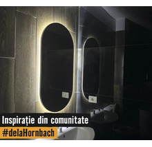 Miroir de salle de bain ovale moderne avec rétroéclairage LED sur un mur aspect bois au-dessus d'un lavabo blanc.