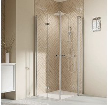 Moderne Eckduschkabine mit Klarglas und silbernen Profilen vor einer gefliesten Wand in einem hellen, elegant gestalteten Badezimmer.