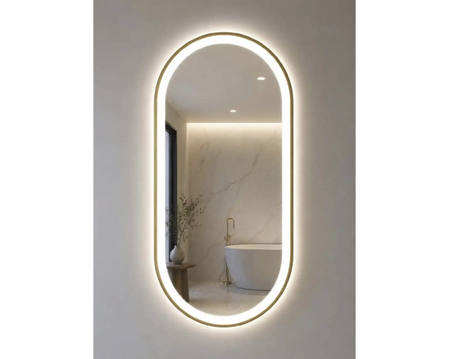 Ovaler Badspiegel mit Goldrahmen und LED-Beleuchtung. Im Spiegel spiegelt sich ein helles Badezimmer mit freistehender Wanne und Marmorwand.