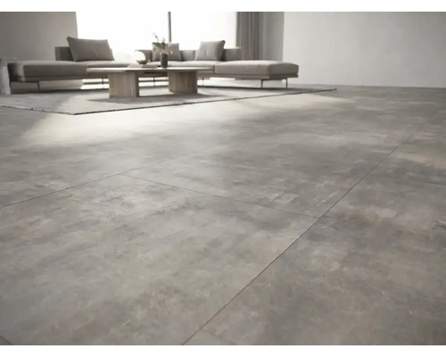 Salon moderne avec des carreaux de sol grand format aspect béton, un canapé gris et une table en bois.