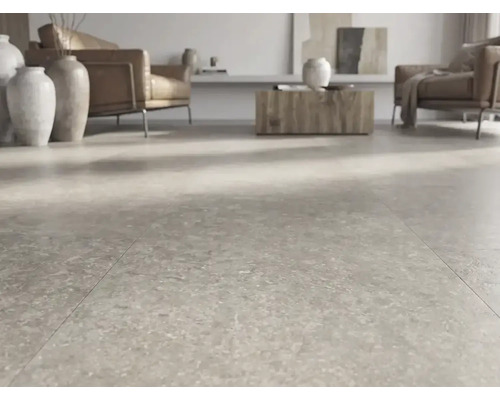 Carrelage de sol moderne aspect pierre dans un salon lumineux et spacieux avec des fauteuils en cuir et des vases décoratifs.