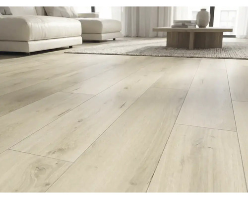 Sol stratifié clair à l'aspect chêne posé en larges lames dans un salon moderne et lumineux avec un canapé blanc.