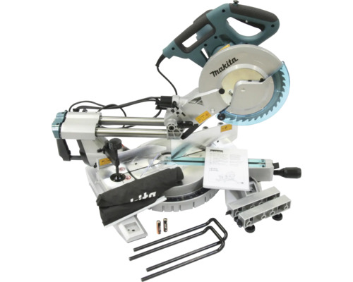 Scie à onglets radiale Makita avec accessoires tels que sac à poussière, serre-joint et manuel d'utilisation.