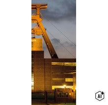 Bâtiment industriel avec tour d’extraction historique au crépuscule et éclairage de la façade en briques. (Image AI modified or generated)