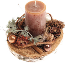 Décoration de table de Noël avec une bougie pilier sur un disque de bois, ornée de pommes de pin, de boules de Noël et de bâtons de cannelle.