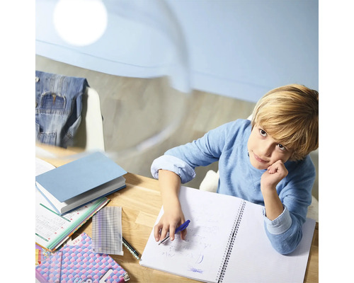 Un garçon étudie sur un bureau en bois avec des manuels scolaires et des fournitures de bureau.