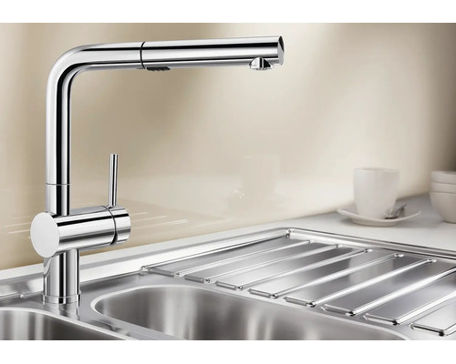 Mitigeur de cuisine moderne avec douchette extractible en métal sur un évier.