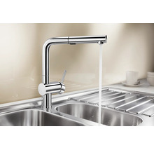 Mitigeur de cuisine moderne en métal avec douchette extractible et eau courante au-dessus d un évier en acier inoxydable.