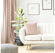 Salon moderne avec canapé blanc, coussin côtelé, plante d'intérieur et rideaux dans un aménagement intérieur lumineux.