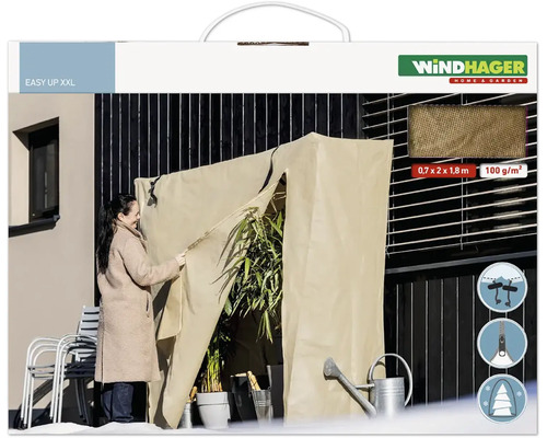 Une femme utilise une housse de protection hivernale Windhager Easy Up XXL sur une terrasse pour protéger les plantes du froid.