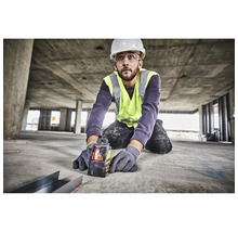 Handwerker mit Schutzkleidung nutzt einen DeWalt Kreuzlinienlaser auf einer Baustelle für präzise Messungen am Boden.