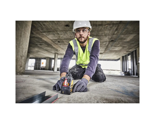 Handwerker mit Schutzkleidung nutzt einen DeWalt Kreuzlinienlaser auf einer Baustelle für präzise Messungen am Boden.