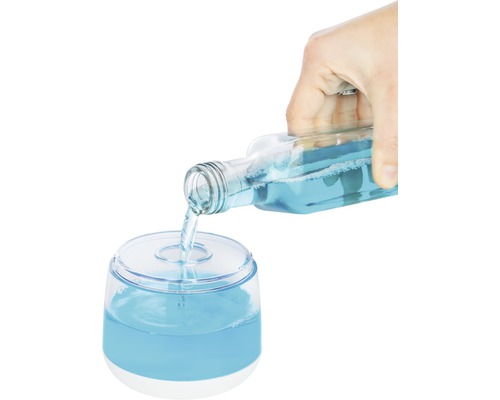 Une main verse du liquide bleu d''une bouteille dans un distributeur.