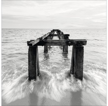 Schwarz-Weiß-Foto einer alten Seebrücke im Meer.