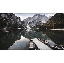 Boote an einem Holzsteg auf einem See mit Bergkulisse