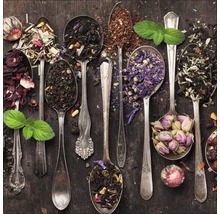 Verschiedene Teesorten in silbernen Löffeln auf dunklem Holzgrund