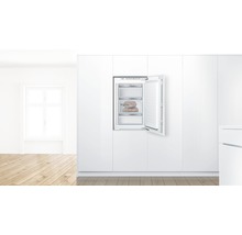 Congélateur intégré avec porte ouverte dans une cuisine blanche