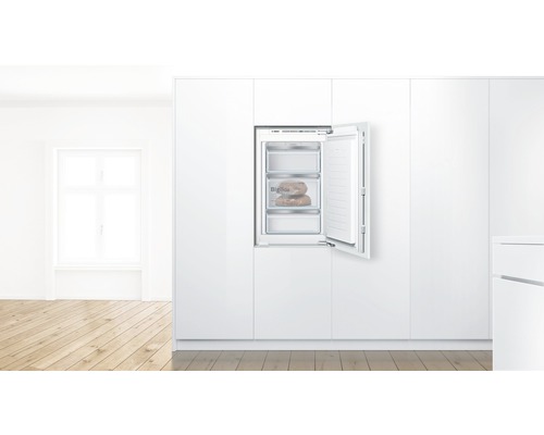 Congélateur intégré avec porte ouverte dans une cuisine blanche
