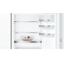 Innenansicht eines Kühlschranks mit Glasablagen und einer Schüssel mit Erdbeeren.