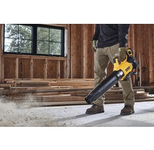 Un homme utilise un souffleur à feuilles sans fil jaune et noir DeWalt sur un chantier.