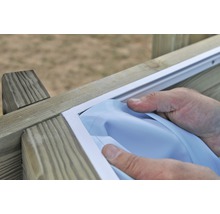 Artisan installant un joint de fenêtre blanc sur une fenêtre en bois