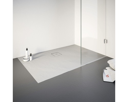 Douche de plain-pied avec caniveau de douche, articles de nettoyage et serviettes.