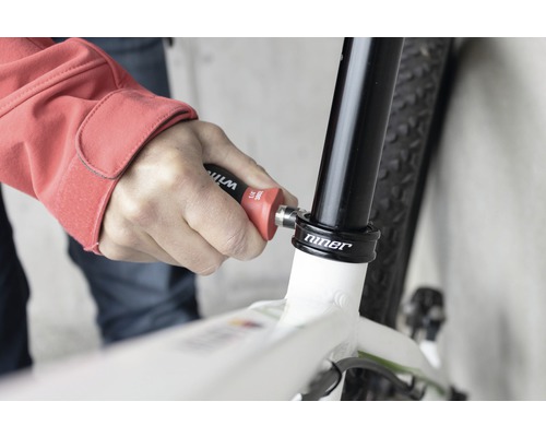 Une personne utilise un outil sur un vélo pour le réparer.