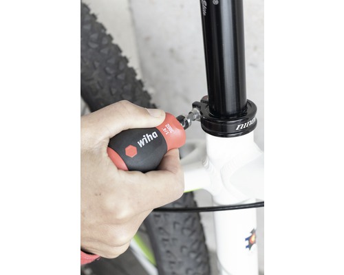 Une personne fixe une tige de selle de vélo à l''aide d''un tournevis Wiha.