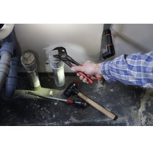 Installation einer Abwasserleitung mit Rohrzange, Hammer und Schraubenzieher